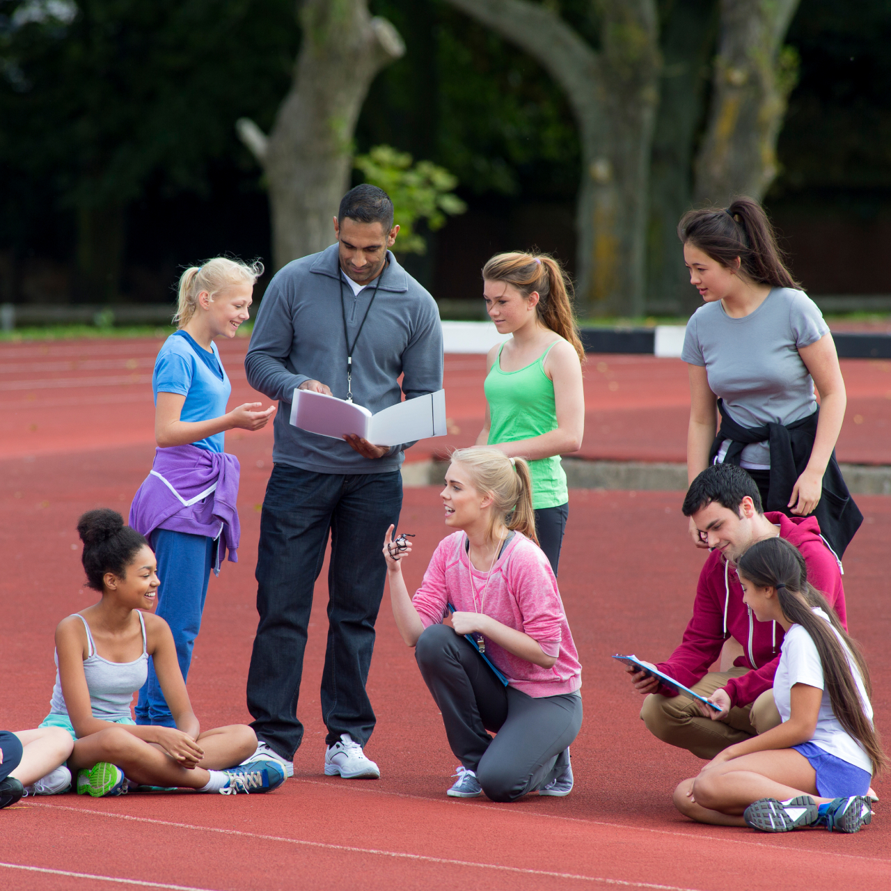 professeur de gymnastique réuni à l'extérieur avec des élèves sur une piste d'athlétisme