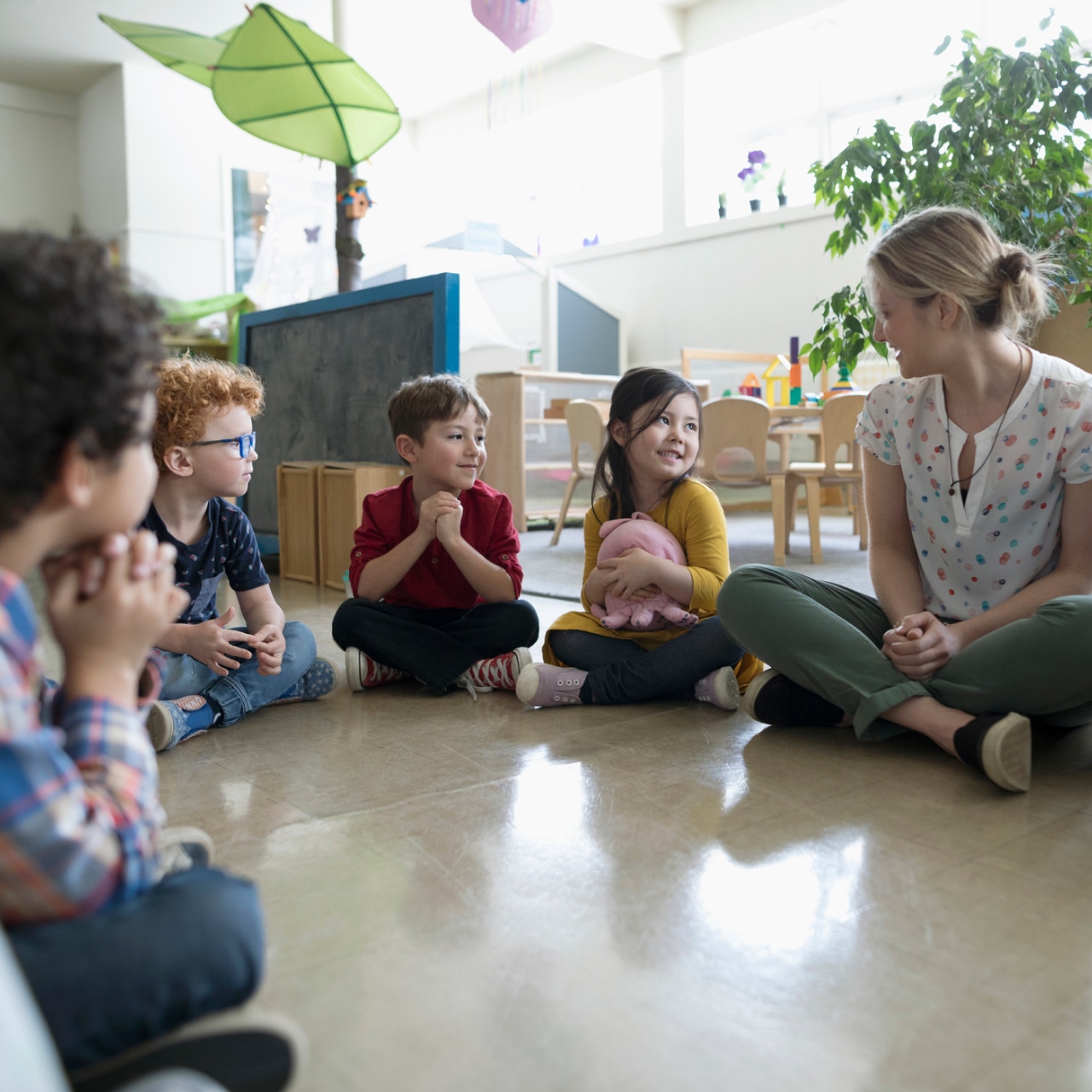 Enseignante assise avec enfants dans une classe du préscolaire